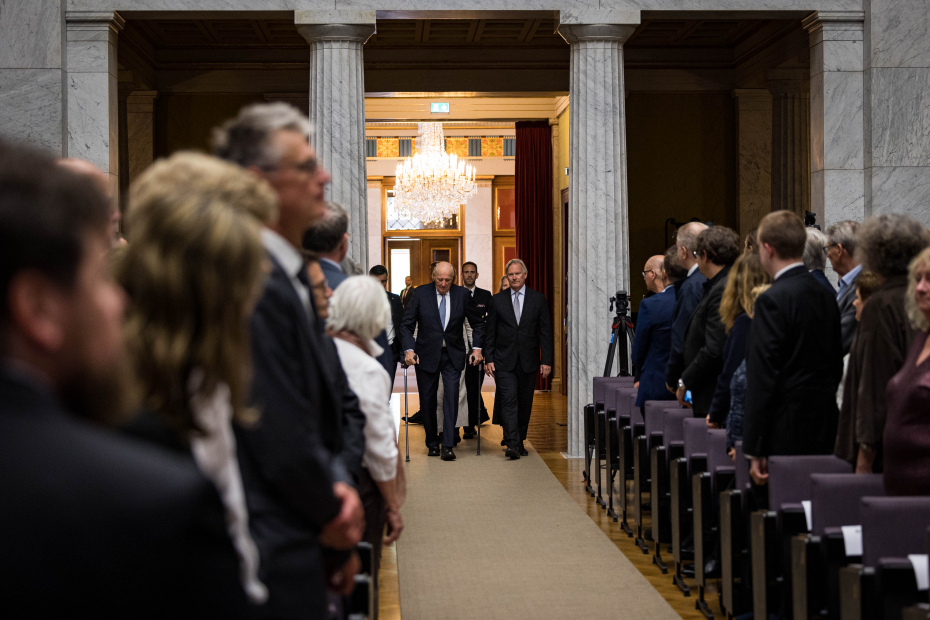 Prosesjon med H.M.Kongen går oppover midtgangen i Aulaen. Ved hans side er viserektor ved UiO Per Morten Sandset.