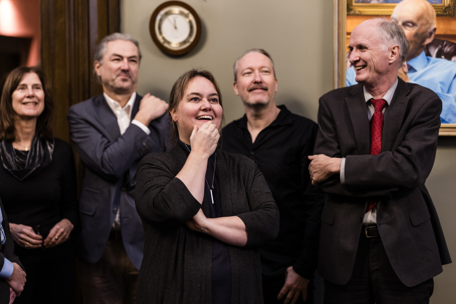 Tre menn og to kvinner smiler