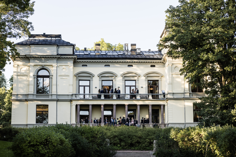 Bilde av Akademiets hus sett fra hagen, med mennesker på balkongen.